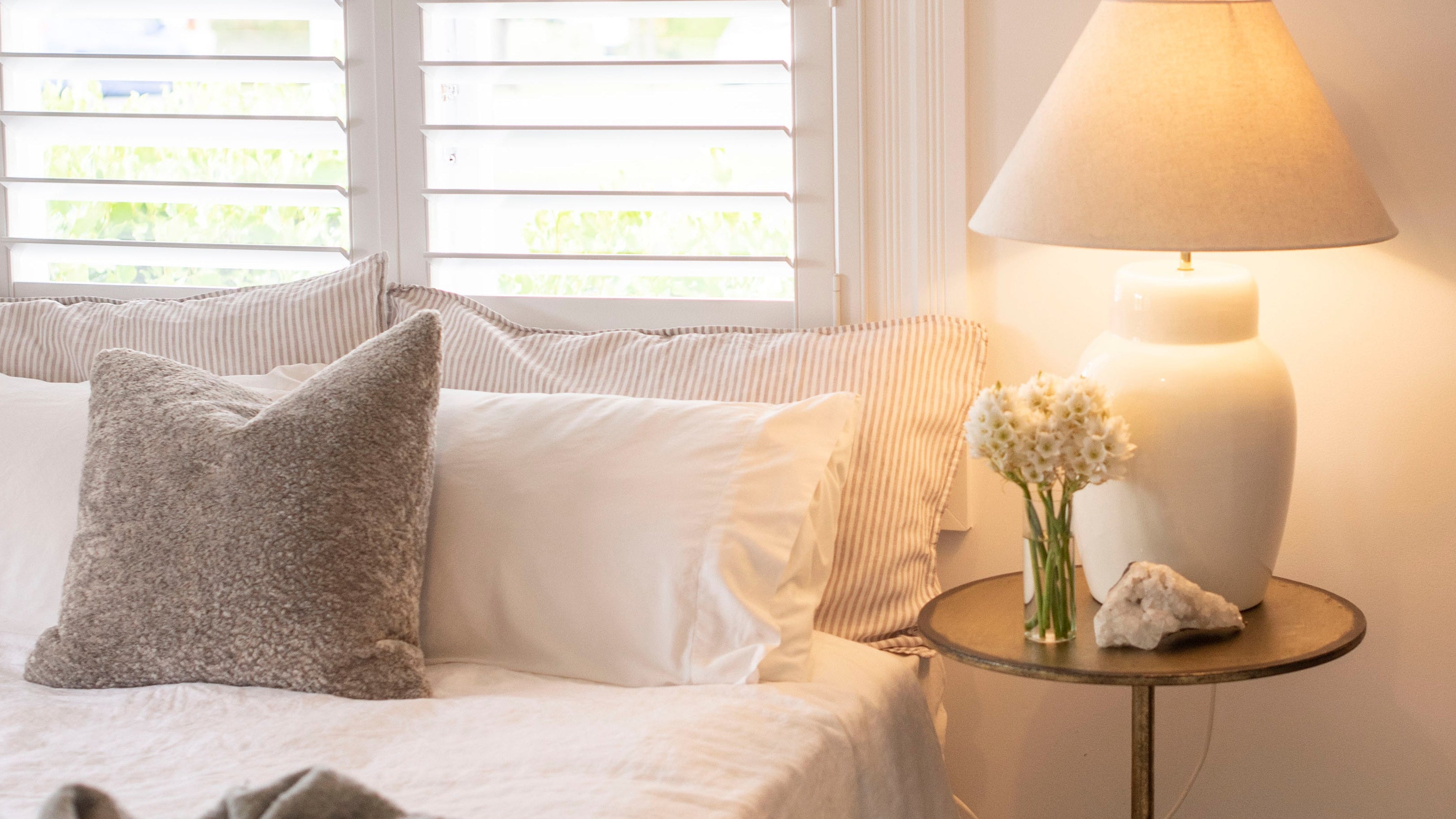 Cozy bedroom with a bed, lamp, and window shutters.